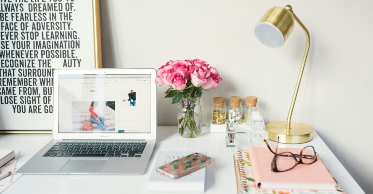 MacBook Air beside gold-colored study lamp and spiral books