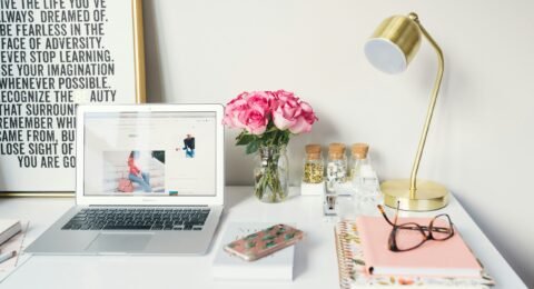 MacBook Air beside gold-colored study lamp and spiral books