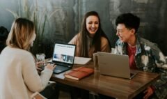 three people sitting in front of table laughing together