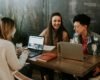 three people sitting in front of table laughing together