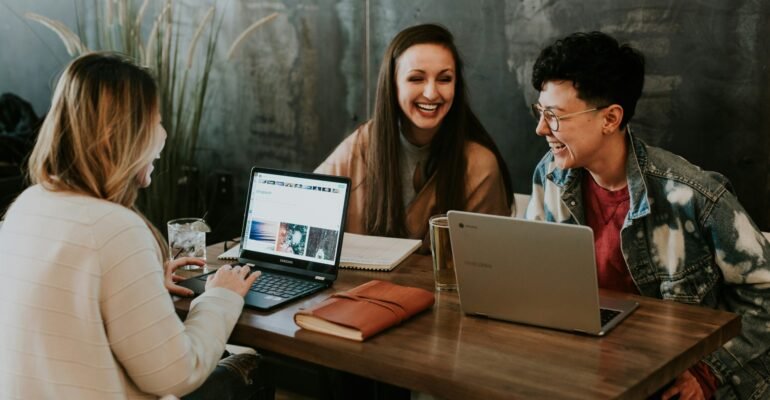 three people sitting in front of table laughing together